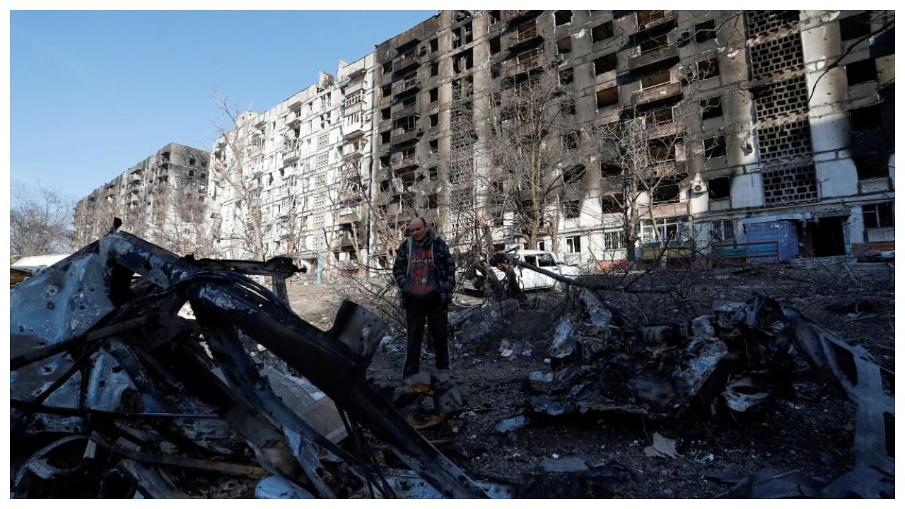A local resident stands next to the wreckage of his car in the courtyard of an apartment building destroyed in the course of Ukraine-Russia conflict in the besieged southern port city of Mariupol, Ukraine March 28, 2022. Credit: Reuters Photo