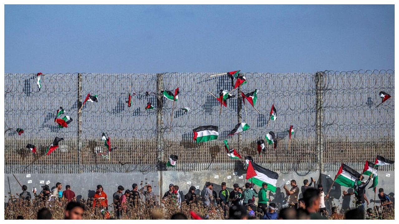 Palestinian flags are fixed to the barbed-wire fence during a 'flag march' demonstration along the border with Israel east of Gaza city on May 18, 2023 in response to the annual Israeli flag march marking 'Jerusalem Day' commemorating the old city's capture by Israel. Credit: AFP Photo