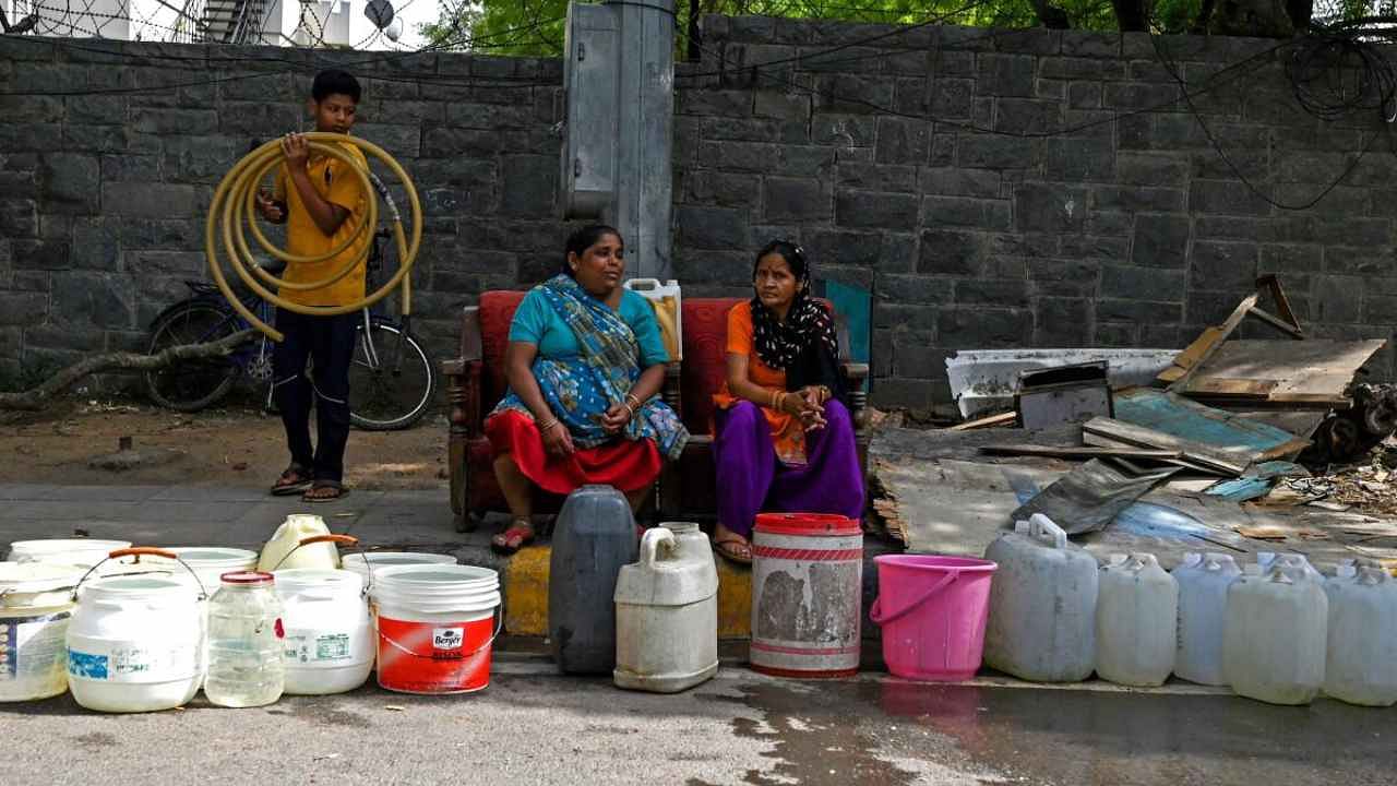 Women sit along a road after collecting water from a municipality tanker in New Delhi on May 22, 2023.  Credit: AFP Photo