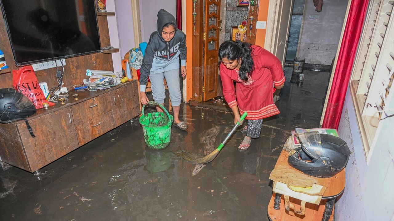 Residents drain slush out of their residence in Mahalakshmi Layout. Credit: DH Photo