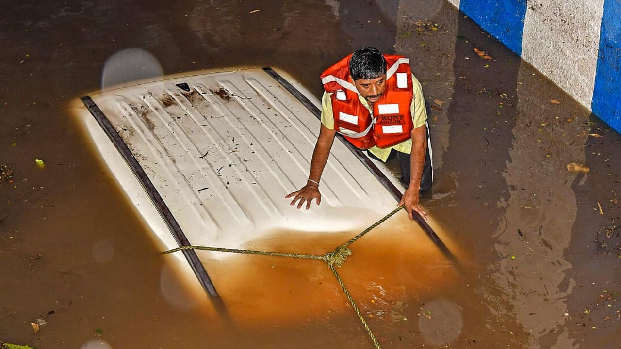 Rescue operation underway after a car got stuck in a waterlogged underpass following heavy rain. Credit: PTI Photo