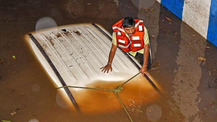 Rescue operation underway after a car got stuck in a waterlogged underpass following heavy rain in Bengaluru. Credit: PTI Photo