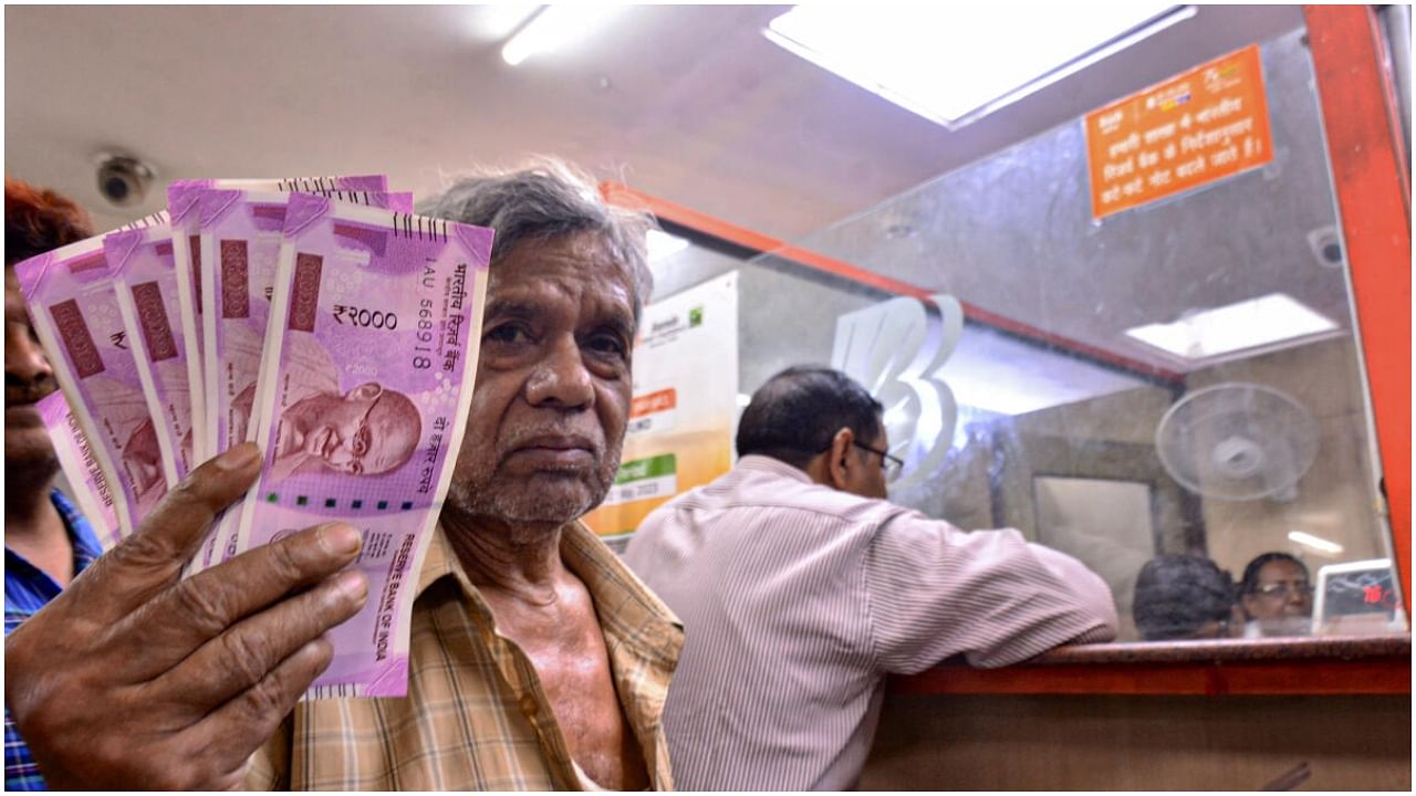 <div class="paragraphs"><p>File Photo: A man holds Rs 2000 currency notes at a bank in Kanpur, Tuesday, May 23, 2023. </p></div>