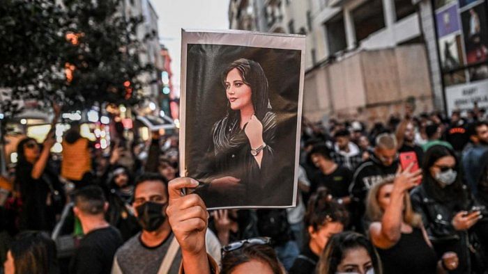 A protester holds a portrait of Mahsa Amini during a demonstration. Credit: AFP File Photo