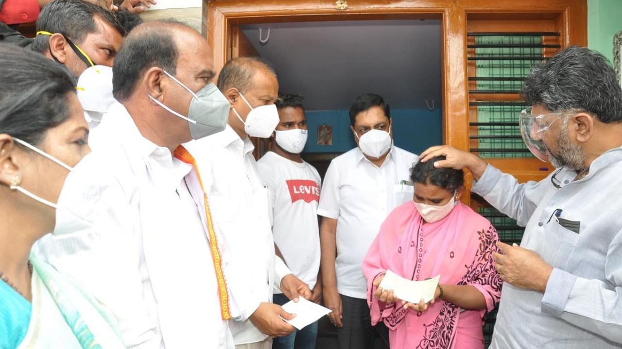 D K Shivakumar, then KPCC president, consoles the family members of oxygen tragedy victims and presents a compensation cheque for Rs 1 lakh, at Palya village, Kollegal taluk, Chamarajanagar district in June 2021. Credit: DH File Photo