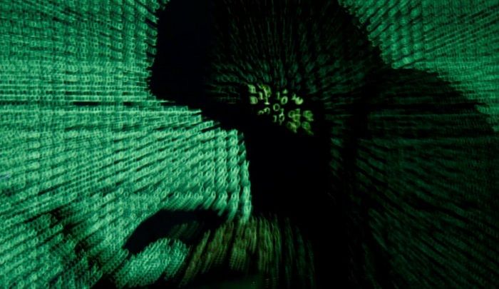 Man holds laptop computer as cyber code is projected on him in this illustration picture. Credit: Reuters File Photo