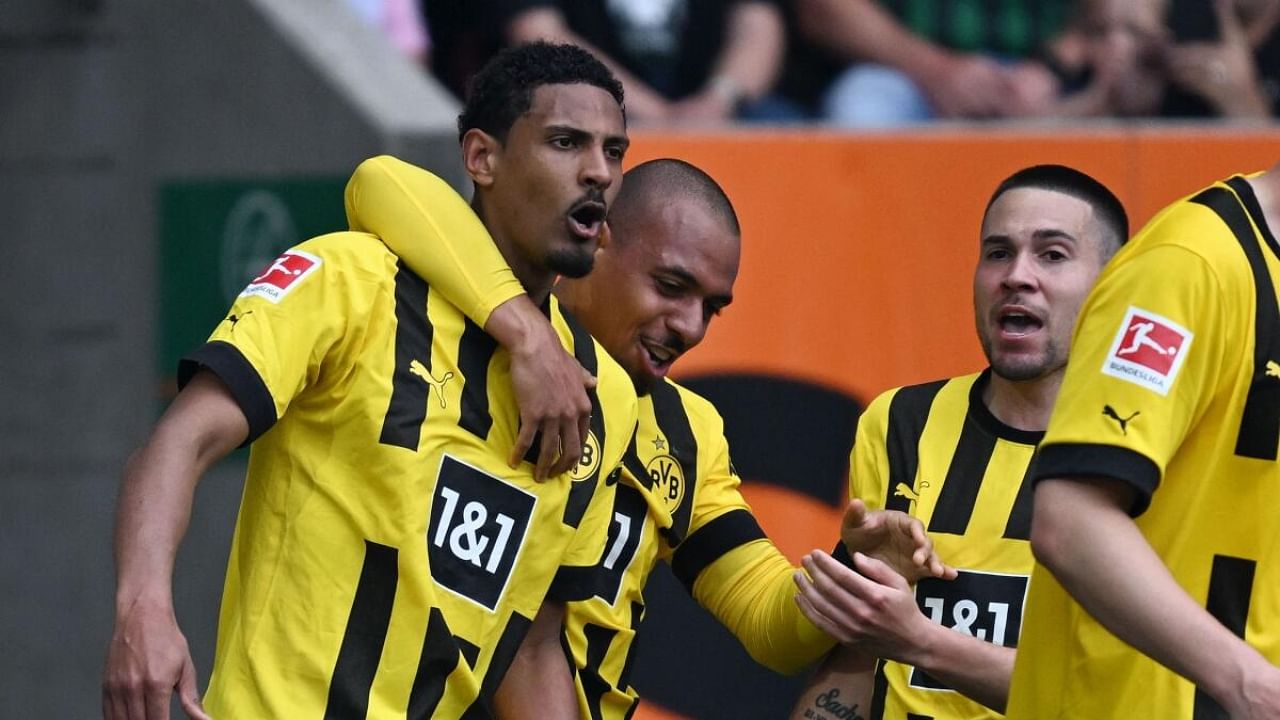 Dortmund's French forward Sebastien Haller (L) celebrates scoring the opening goal with his teammate Dortmund's Dutch forward Donyell Malen (C) and Dortmund's Portuguese defender Raphael Guerreiro during the German first division Bundesliga football match between FC Augsburg and BVB Borussia Dortmund in Augsburg. Credit: AFP Photo