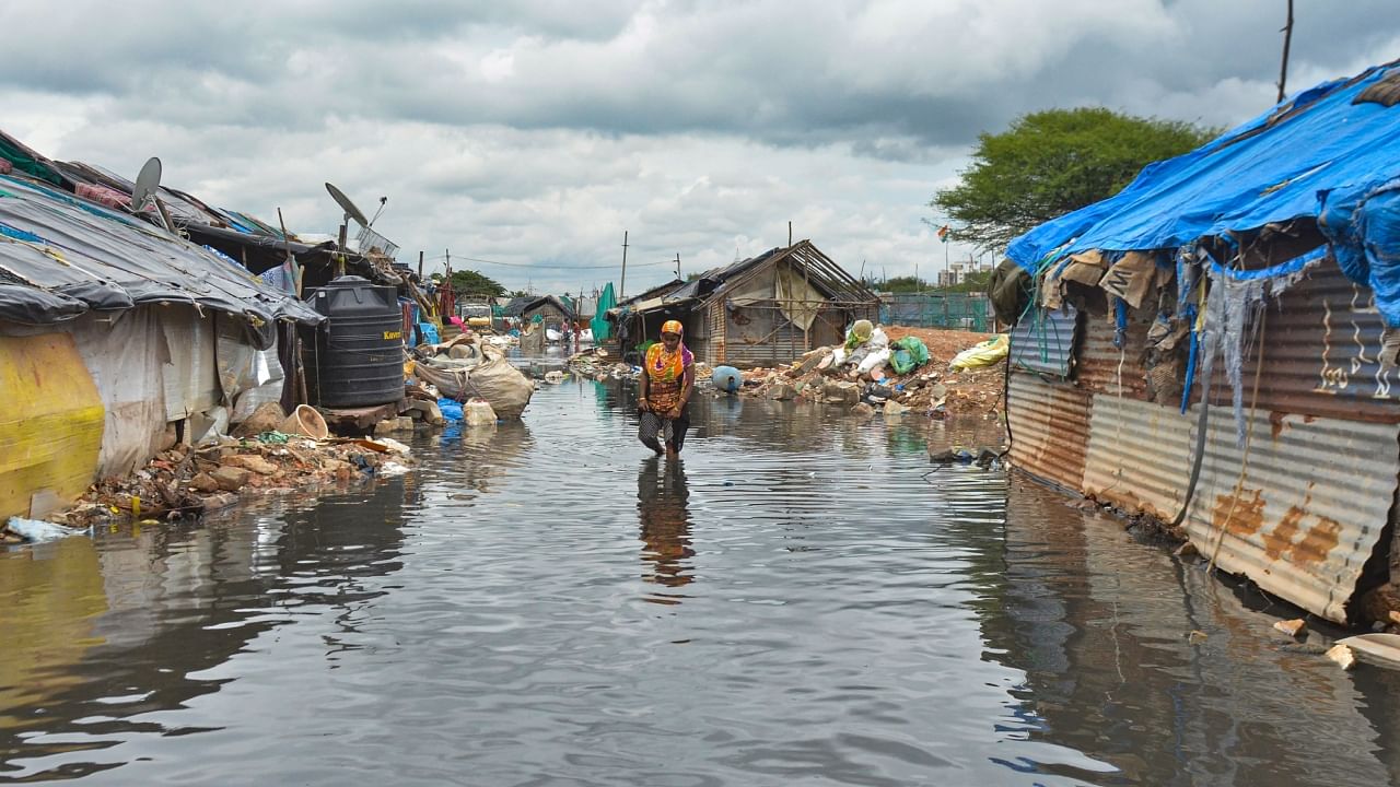 A woman walks through a waterlogged Munnekolala slum area due to overflowing of the Varthur lake, following heavy monsoon rains in Bengaluru, Thursday, Sep. 8, 2022. Credit: PTI Photo