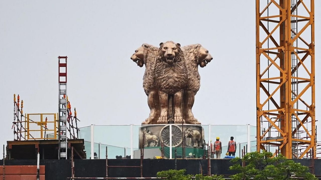 Workers stand next to the newly inaugurated 'National Emblem' installed on the roof of the new Indian parliament building. Credit: AFP File Photo