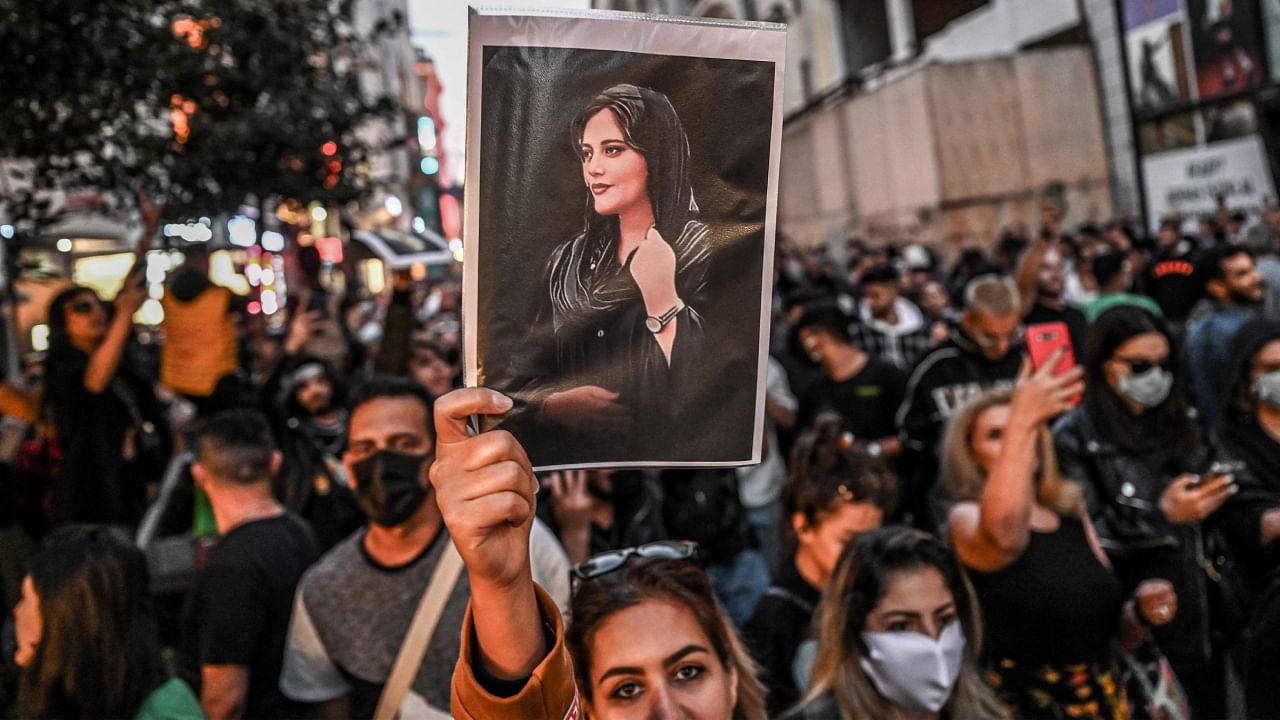 A protester holds a portrait of Mahsa Amini during a demonstration. Credit: AFP Photo