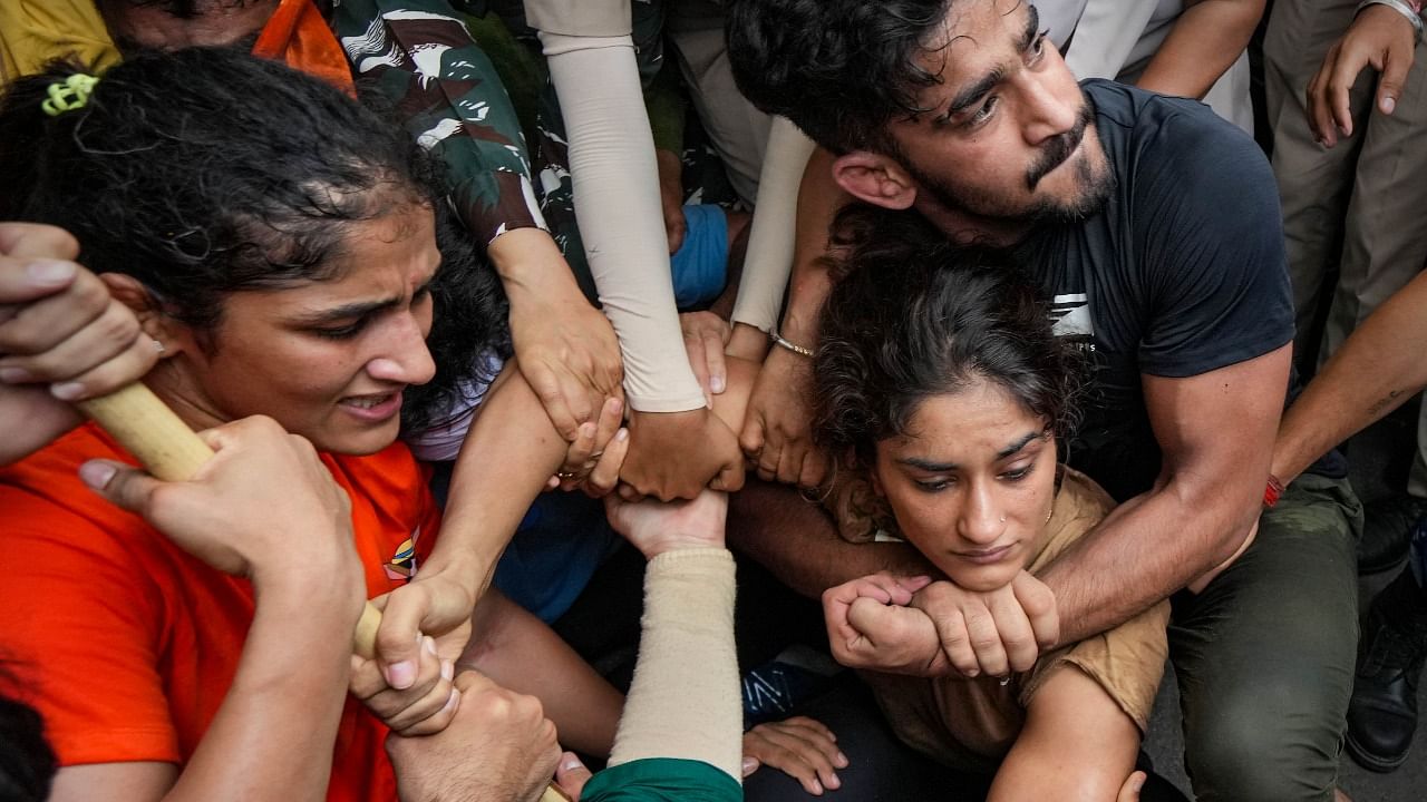 Security personnel detain wrestlers Vinesh Phogat and Sangeeta Phogat during wrestlers' protest march towards new Parliament building. Credit: PTI Photo