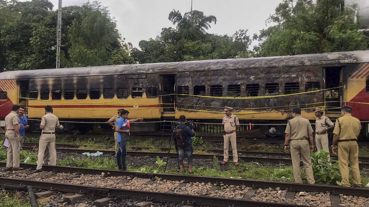 Police personnel inspect the Alappuzha-Kannur Executive Express train which caught fire, at a railway station in Kannur. Credit: PTI Photo