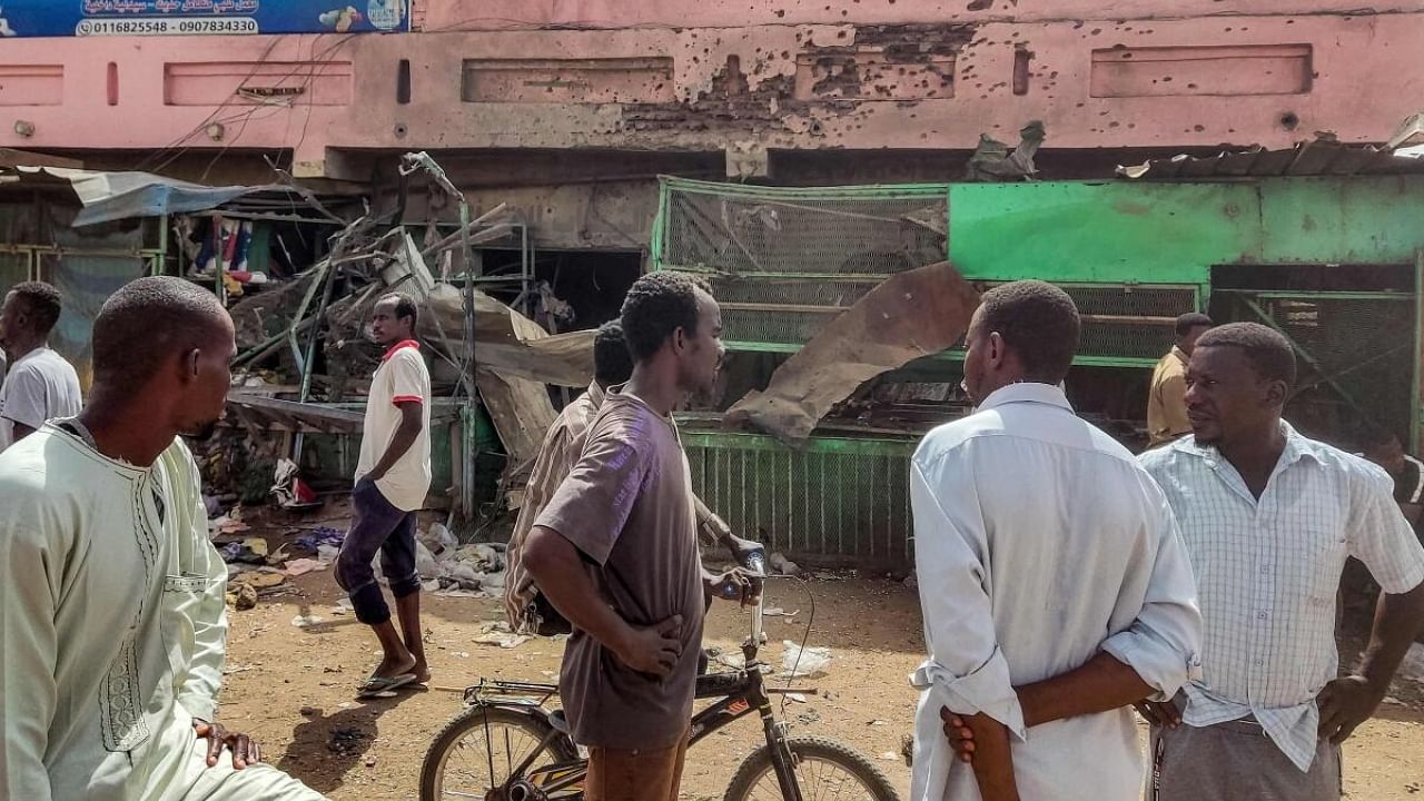 People walk past a medical centre building riddled with bullet holes at the Souk Sitta (Market Six) in the south of Khartoum. Credit: AFP Photo
