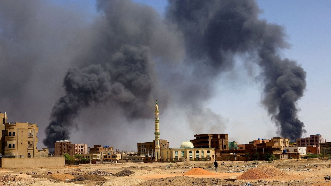 A man walks while smoke rises above buildings after aerial bombardment, during clashes between the paramilitary Rapid Support Forces and the army in Khartoum North, Sudan. Credit: Reuters Photo