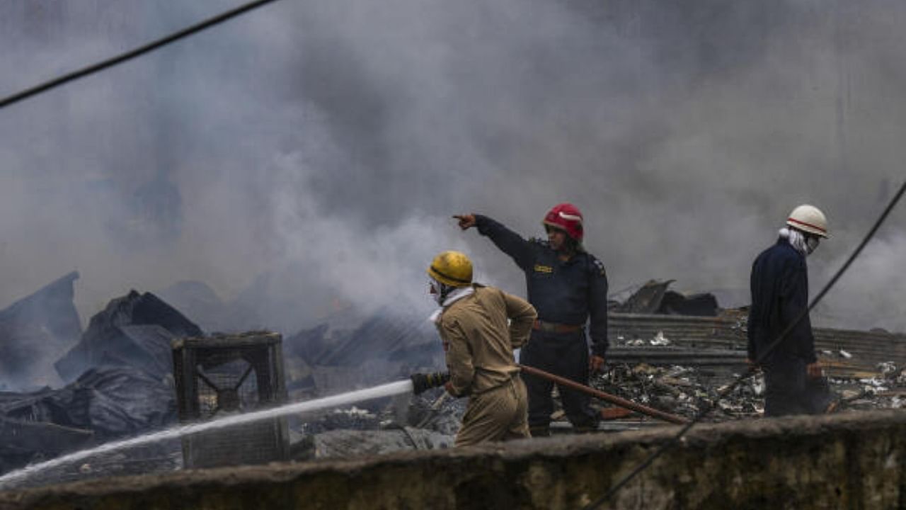 Fire men douse a fire which broke out in an open area at a slum in Jahangirpuri area, in New Delhi. Credit: PTI Photo