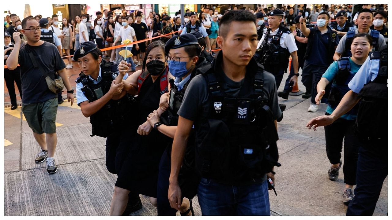 Police detain a woman with paper flowers in downtown on the 34th anniversary of the 1989 Beijing's Tiananmen Square crackdown. Credit: Reuters Photo