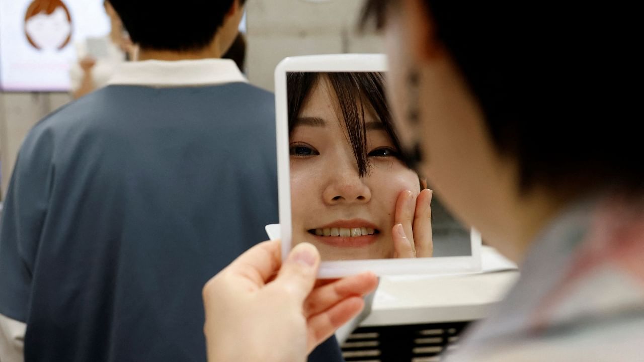 A student practices smiling with a mirror at a smile training course at Sokei Art School in Tokyo, Japan, May 30, 2023. Credit: Reuters Photo