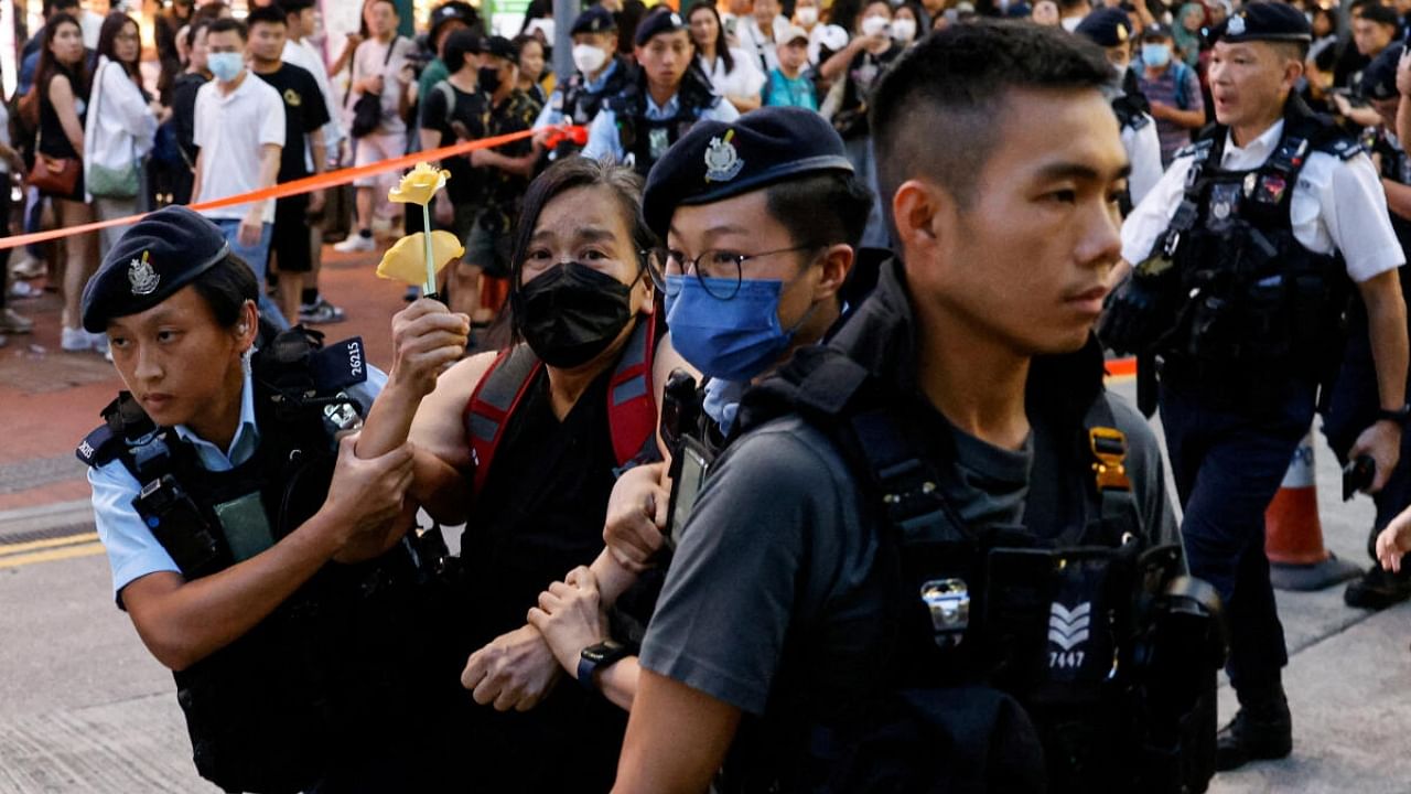 Police detain a woman with paper flowers in downtown on the 34th anniversary of the 1989 Beijing's Tiananmen Square crackdown, near where the candlelight vigil is usually held, in Hong Kong, China June 4, 2023. Credit: Reuters Photo