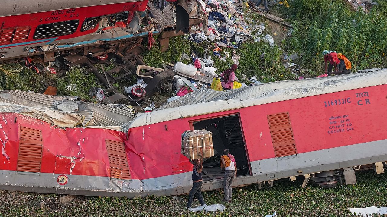 Porters carry goods collected from mangled coaches at triple train mishap site. Credit: PTI Photo