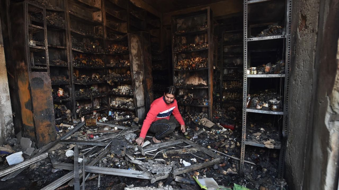  A shopkeeper sorts through the charred remains of a vandalized and burned shop post the 2020 Delhi riots. Credit: PTI File Photo