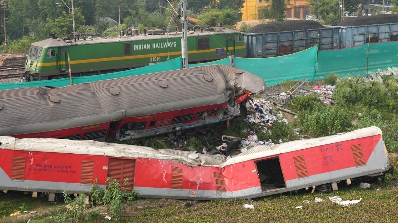 A train runs past derailed coaches after train services resumed on the section where the accident happened on Friday, near Bahanga Bazar railway station in Balasore district, Tuesday, June 6, 2023. Credit: PTI Photo