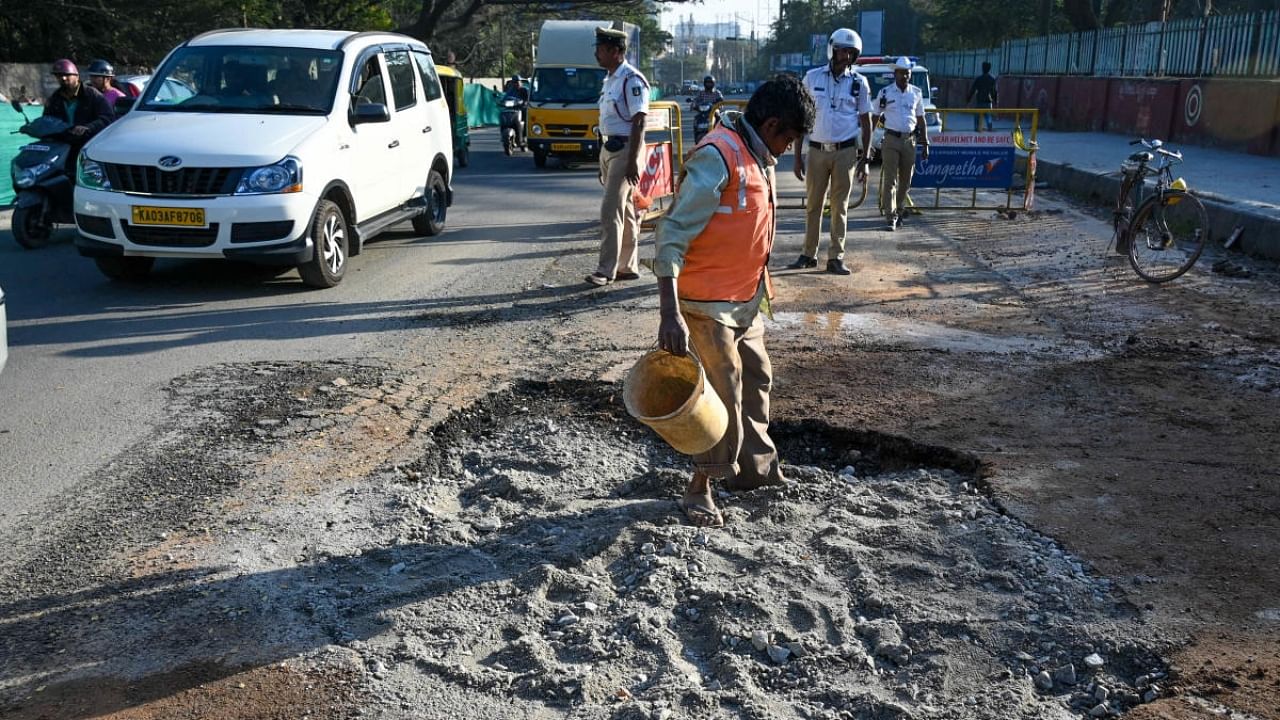 A pothole was created after a possible water leak on the busy Hosur Road near Christian Cemetery. BBMP, BWSSB and traffic personnel were present at the spot. Credit: DH Photo