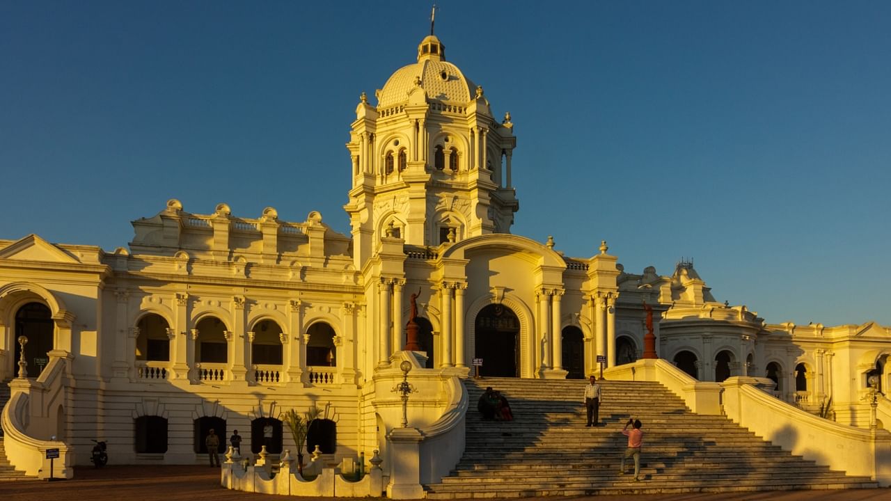The setting sun paints the Ujjayanta Palace yellow in the city of Agartala as visitors take pictures of themselves on its stairs. Credit: iStock Photo
