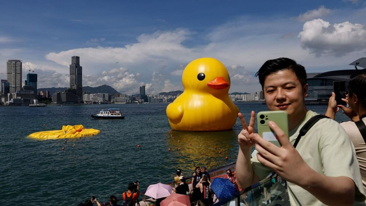 Man poses for a photo with the inflatable yellow ducks created by Dutch artist Florentijn Hofman, one of which is already deflated, at Victoria Harbour in Hong Kong. Credit: Reuters Photo