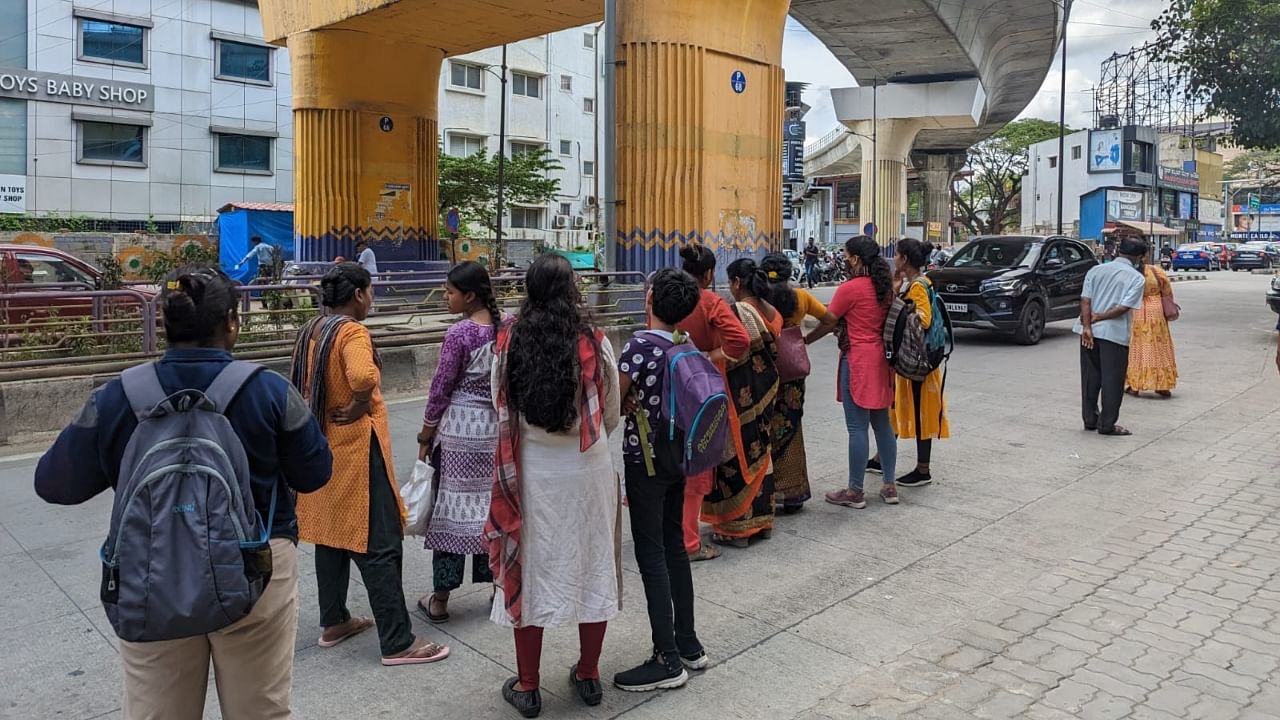 Women wait at the Indiranagar KFC bus stop to use the free bus travel scheme soon after its launch on Sunday. They carried their Aadhaar and other IDs, and boarded the BMTC's route number (314H) to Majestic. Credit: DH Photo/Udbhavi Balakrishna