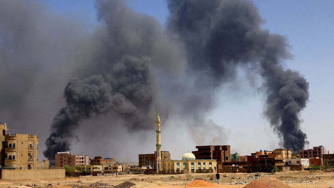 A man walks while smoke rises above buildings after aerial bombardment. Credit: Reuters File Photo