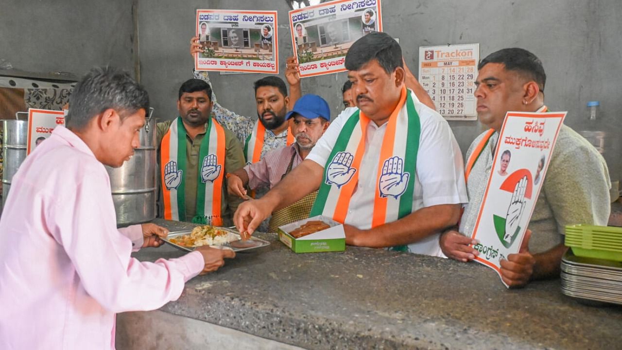 Congress workers distributing sweet to people in Indira Canteen. Credit: DH Photo 
