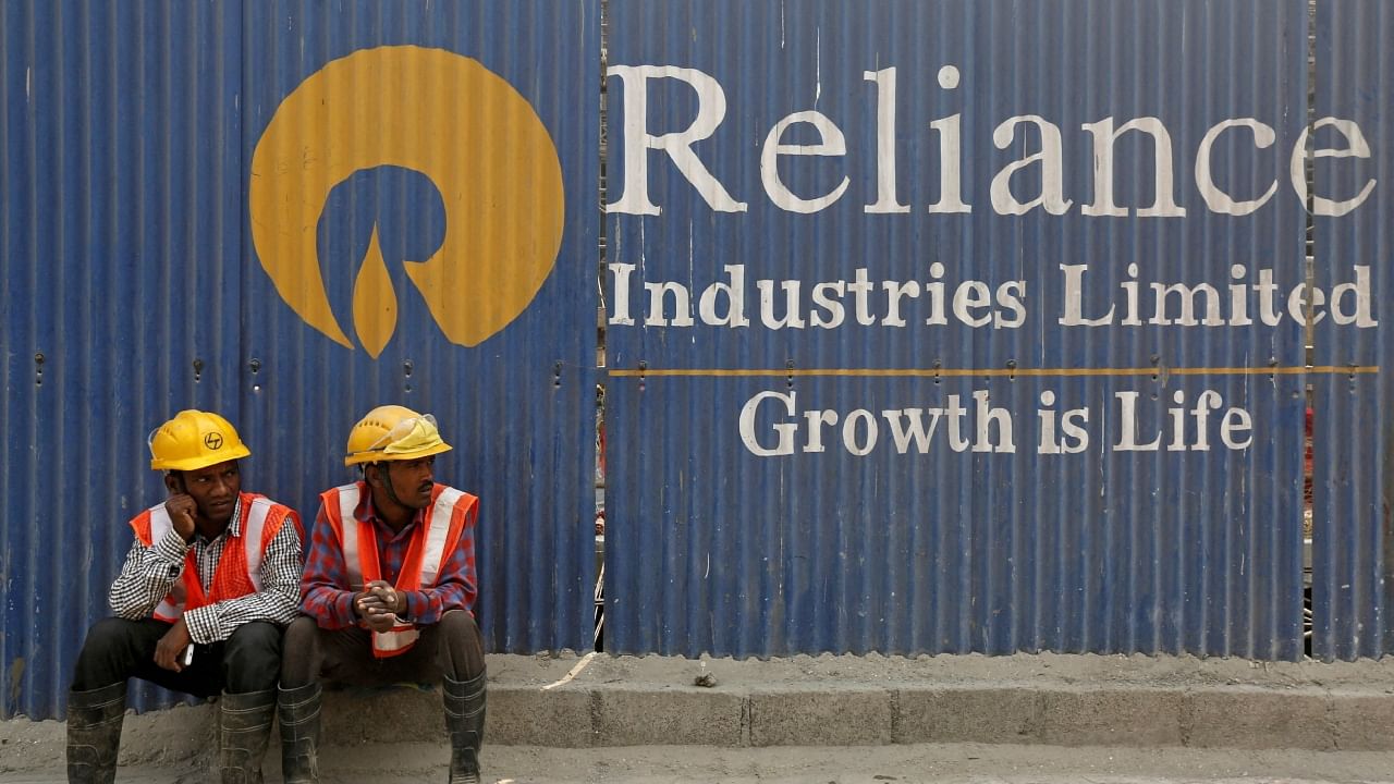  Labourers rest in front of an advertisement of Reliance Industries Limited at a construction site in Mumbai, March 2, 2016. Credit: Reuters File Photo