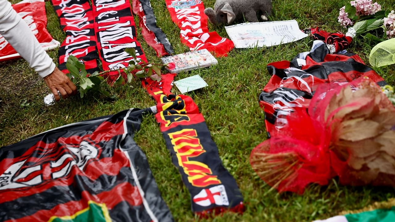 A person lays a flower among football memorabilia near Villa San Martino, the residence of former Italian Prime Minister Silvio Berlusconi, to which his body was transported following his death, in Arcore near Milan, Italy, June 13, 2023. Credit: Reuters Photo