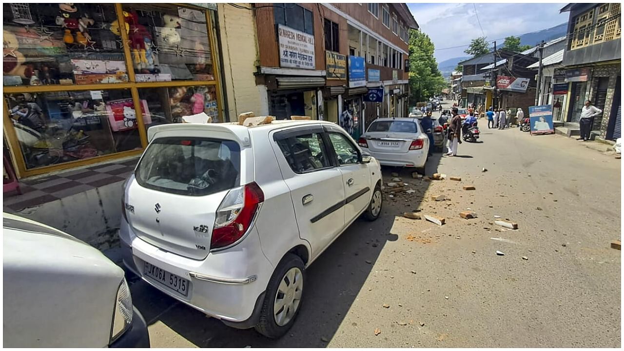 Doda: Brick bats scattered on vehicles and roads due to partial collapse a building after a massive earthquake struck Chenab region, in Doda, Tuesday, June 13, 2023. Dozens of government buildings, shopping complexes and offices got partially damaged after the tremor.  Credit: PTI Photo