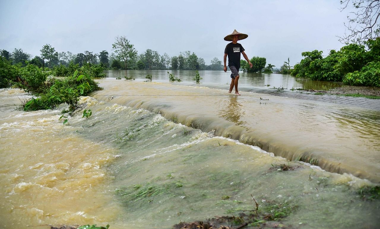 A villager crosses a flooded area following heavy rainfall, in Nagaon district of Assam, Sunday, June 18, 2023. Credit: PTI Photo