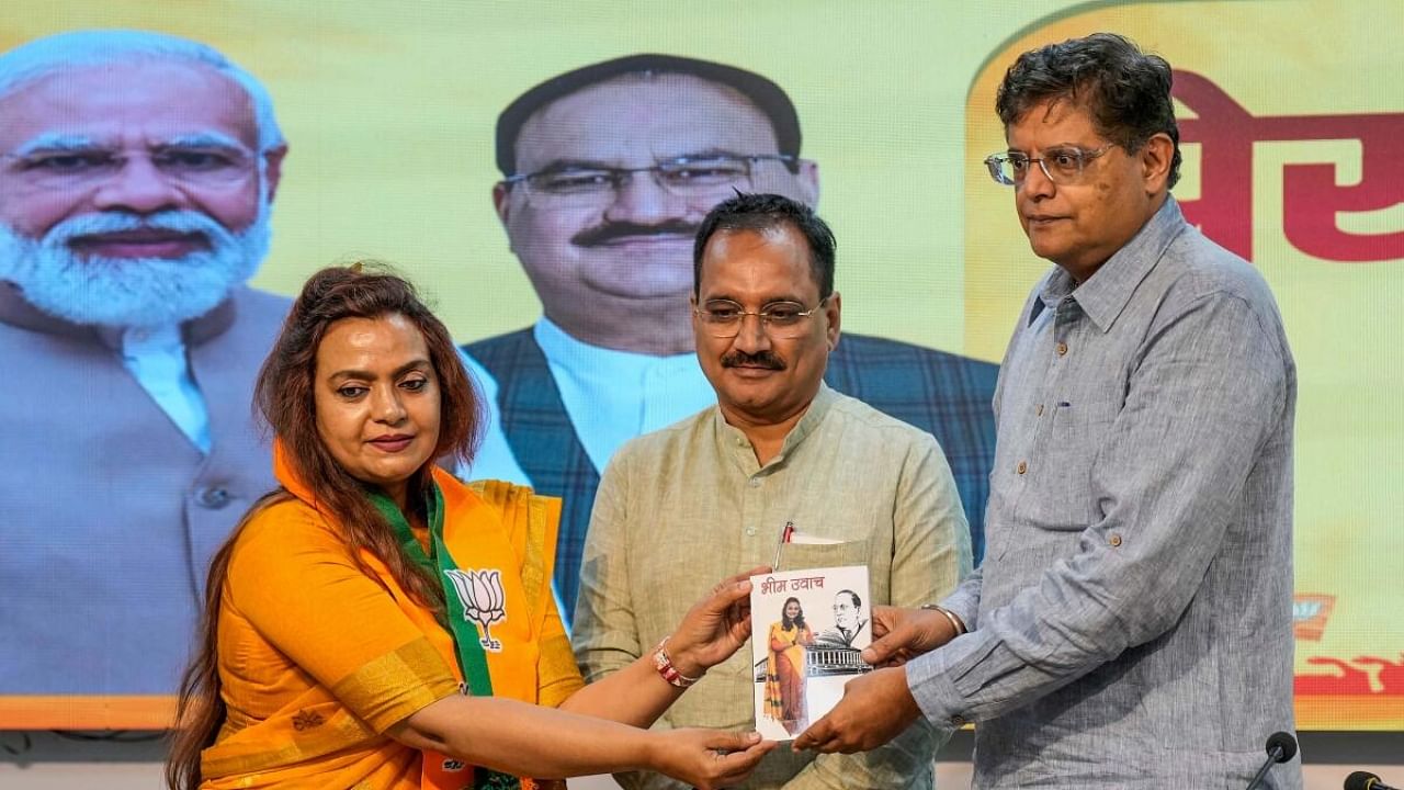 Former IRS officer Preeta Harit presents her book to Delhi BJP President Virendra Sachdeva and BJP Delhi incharge Baijayant Panda after she joined the party, in New Delhi. Credit: PTI Photo