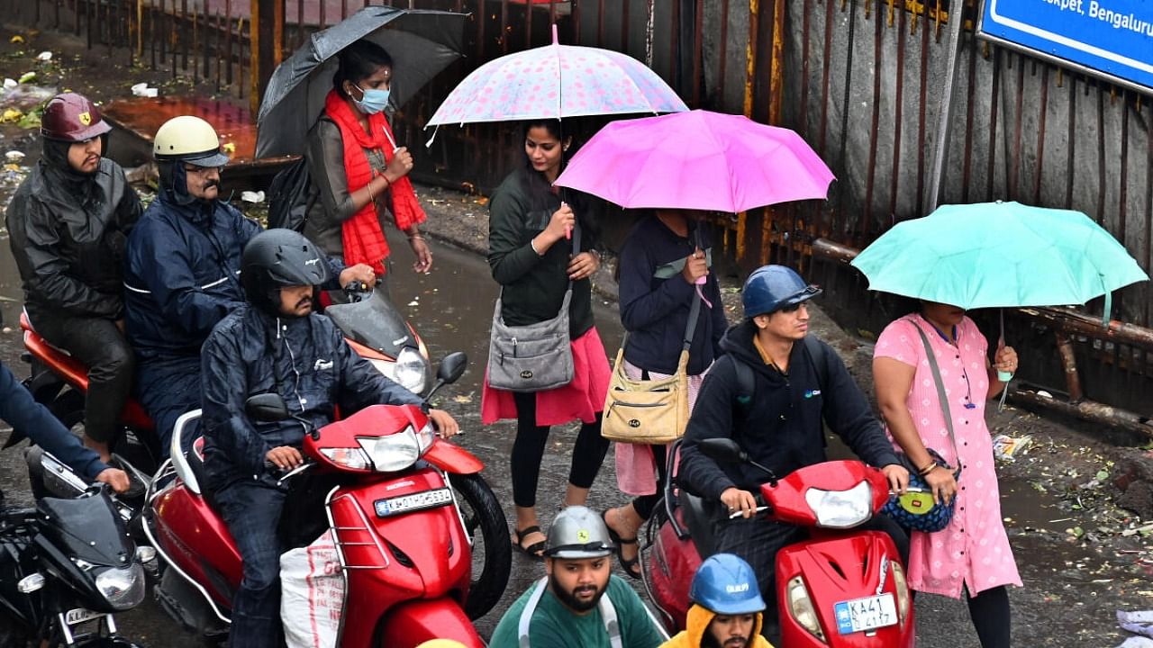 People hold umbrellas and wear raincoats as the city witnesses incessant rain on Tuesday, June 20, 2023. Credit: DH Photo/PUSHKAR V