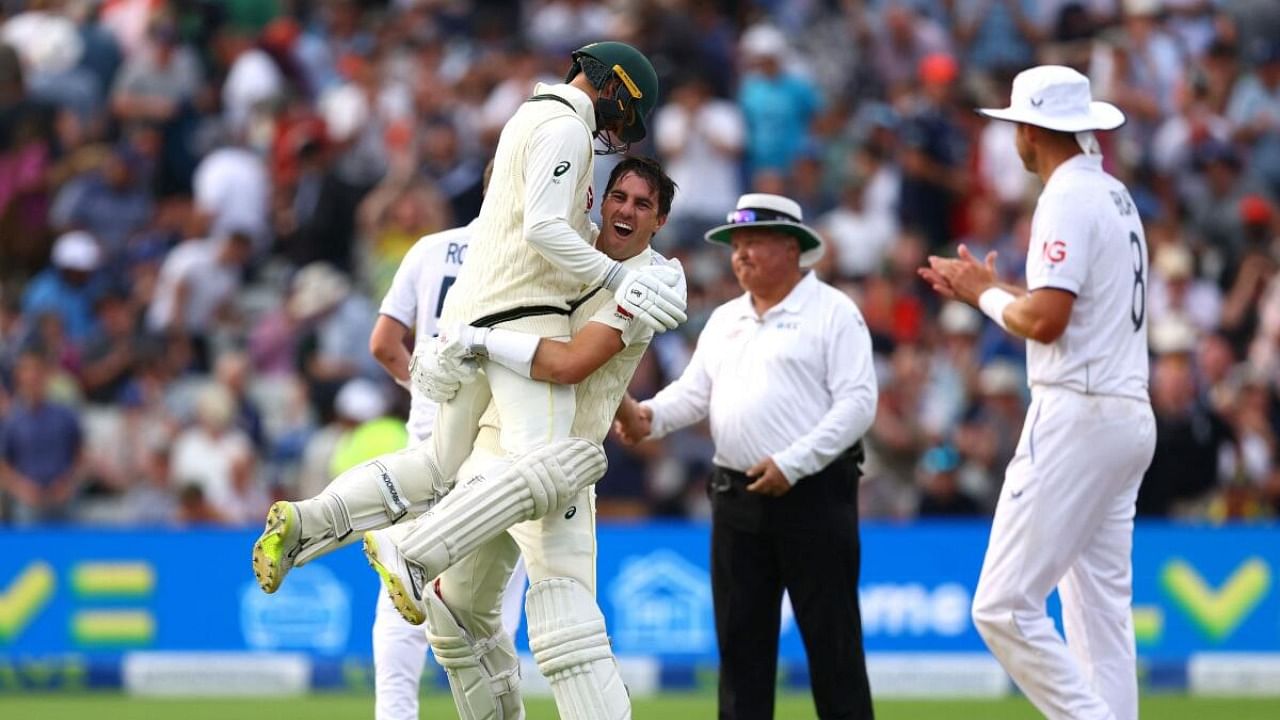 Australia's Pat Cummins and Nathan Lyon celebrate after winning the first test by 2 wickets as England's Stuart Broad applauds. Credit: Reuters Photo