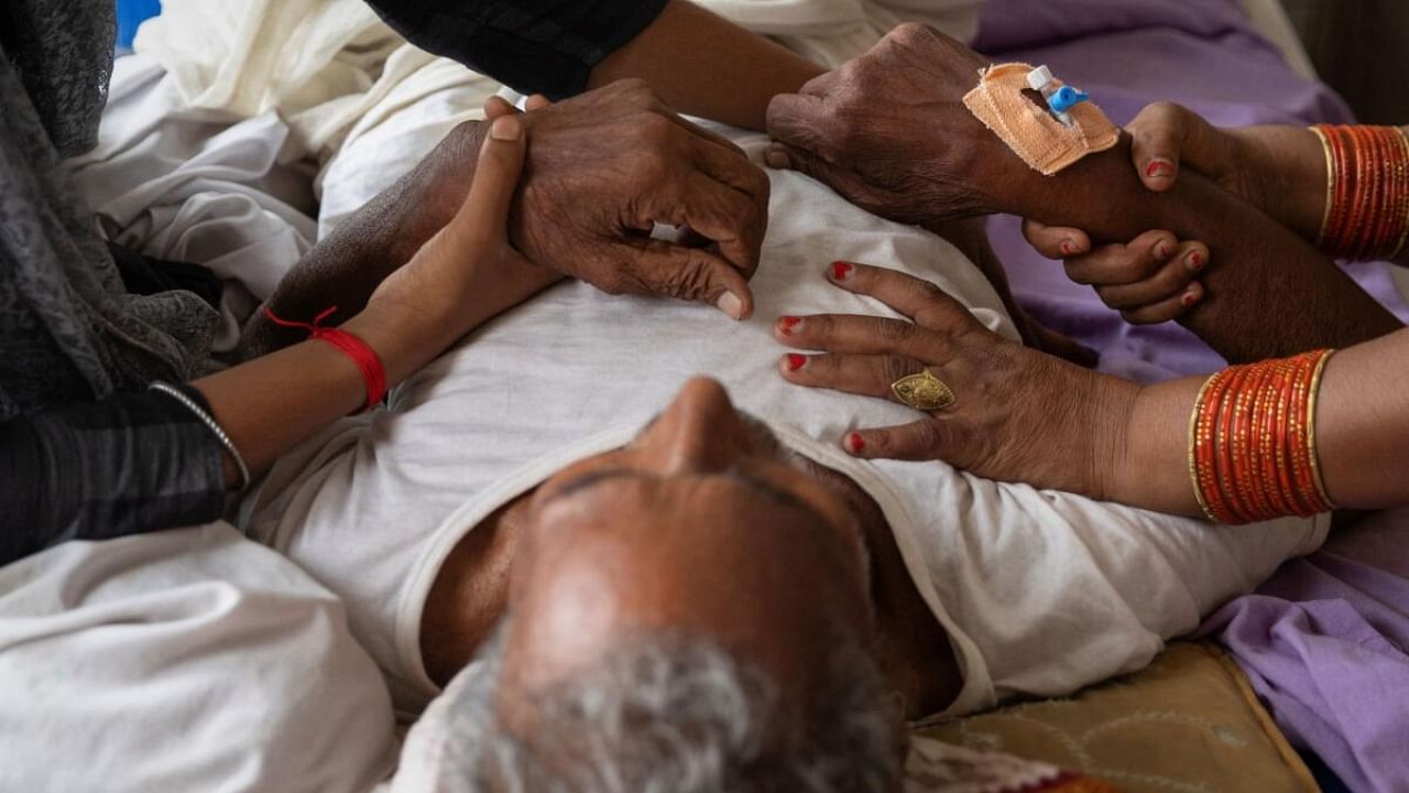 Relatives hold hands of Jagdev Ram, 80, who is suffering from breathing difficulties suspected to be heat-related, as he lies on a bed inside a hospital ward in Ballia District in the northern state of Uttar Pradesh, India, June 21, 2023. Credit: Reuters Photo