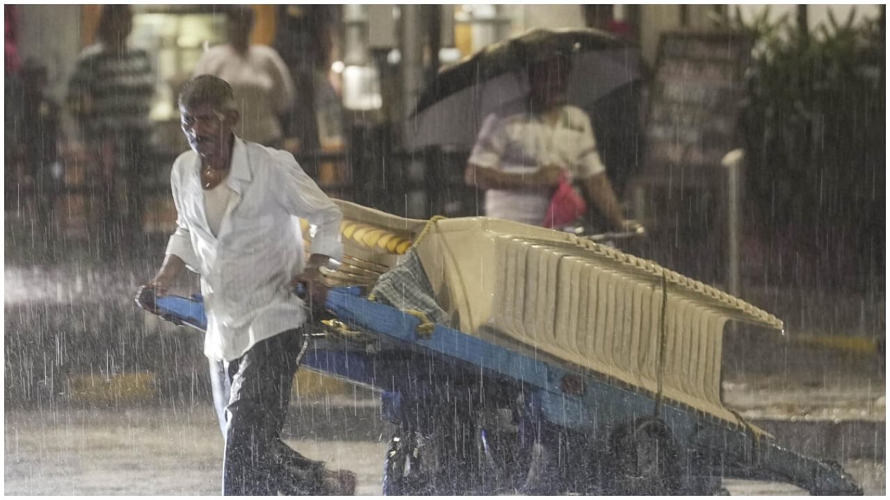 Mumbai: A man pulling a cart crosses a road amid rainfall as the southwest Monsoon advances over Mumbai, at Dadar, Saturday, June 24, 2023.  Credit: PTI Photo