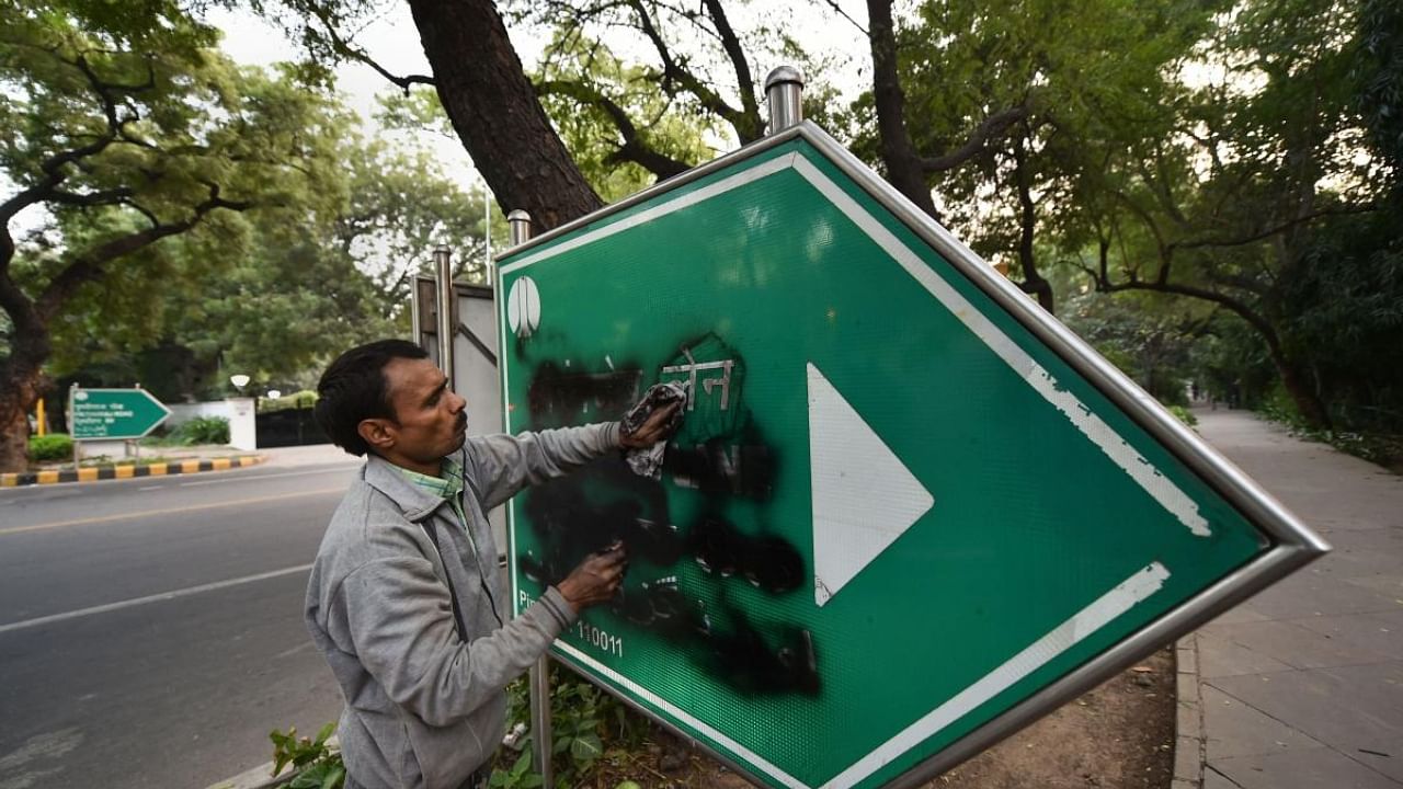 A man cleans the Aurangzeb Lane singboard that was blackened by Shiromani Akali Dal (SAD) MLA Manjinder Singh Sirsa and other Delhi Sikh Gurdwara Management Committee (DSGMC) members, in New Delhi, Sunday, Dec. 1, 2019. Credit: PTI Photo