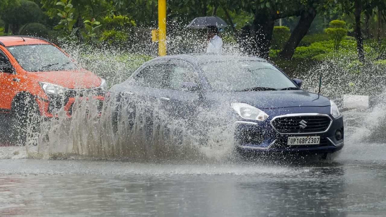 Commuters wade through a waterlogged road during Monsoon rainfall, in New Delhi. Credit: PTI Photo