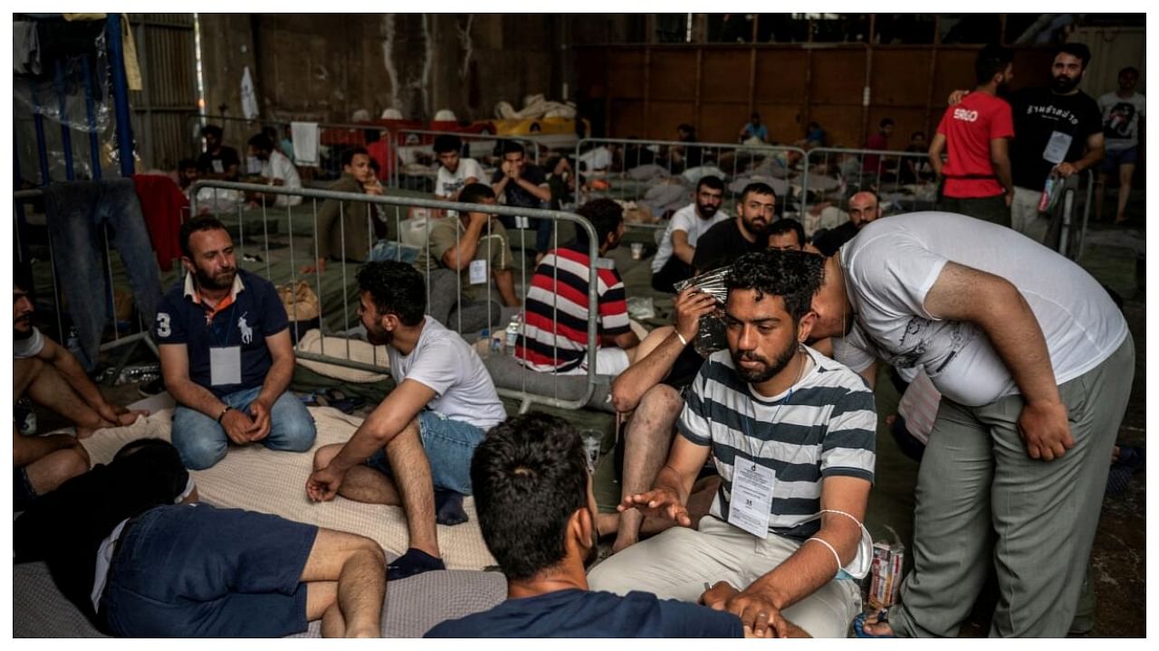 Migrants who were rescued at open sea off Greece along with other migrants, after their boat capsized, are seen inside a warehouse, used as shelter, at the port of Kalamata, Greece, June 15, 2023. Credit: Reuters Photo