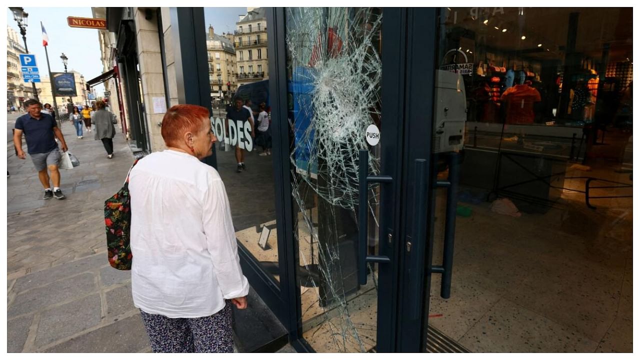 A woman looks at the damaged window of a Jott store vandalised during a night of clashes between protesters and police following the death of Nahel, a 17-year-old teenager killed by a French police officer in Nanterre during a traffic stop, at Rue de Rivoli in Paris, France, June 30, 2023. Credit: Reuters Photo