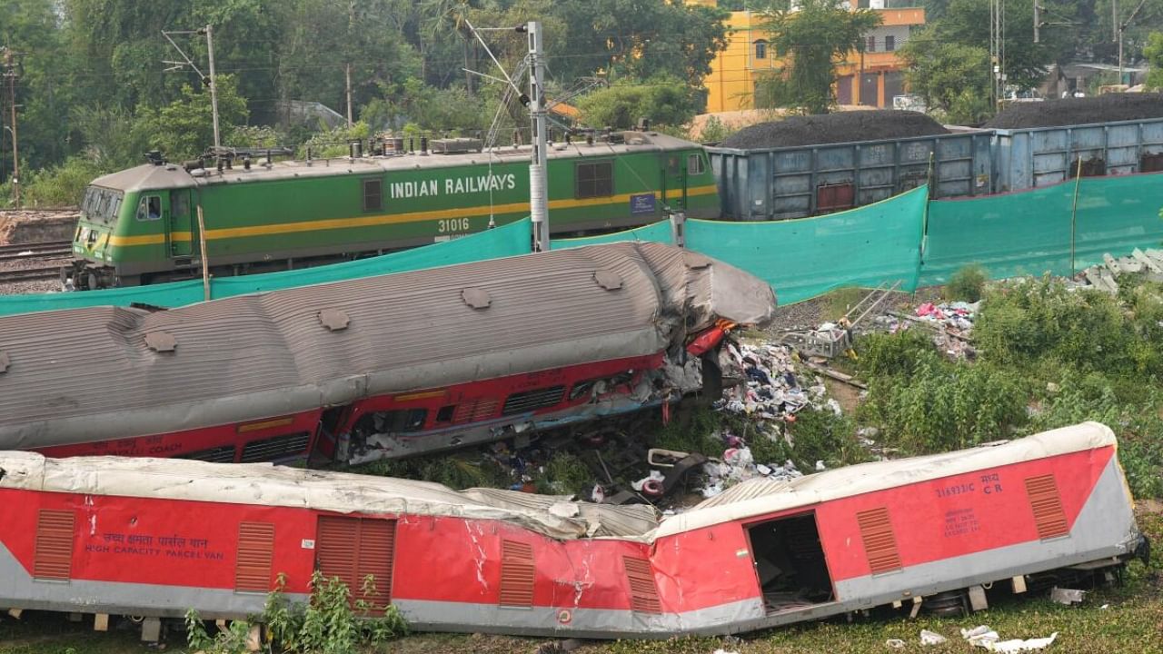 A train runs past derailed coaches after train services resumed on the section where the accident happened. Credit: PTI Photo