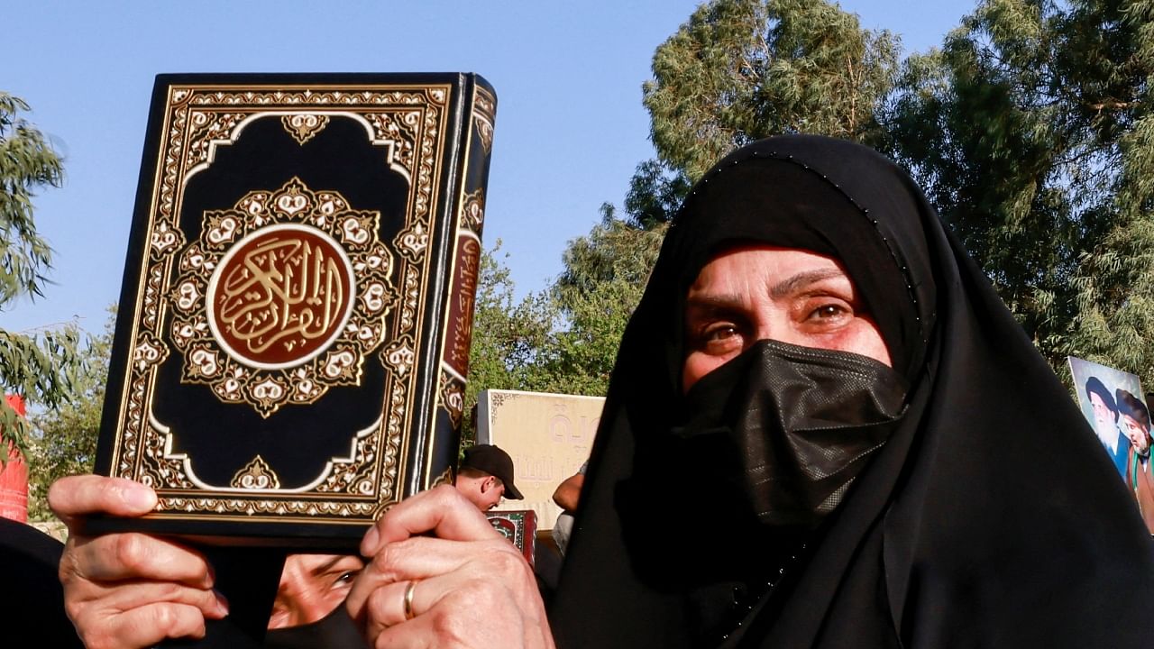 A woman holds a copy of the Koran during a protest against a man who tore up and burned a copy of the Koran outside a mosque in the Swedish capital Stockholm, near the Swedish embassy in Baghdad, Iraq, June 30, 2023. Credit: Reuters Photo