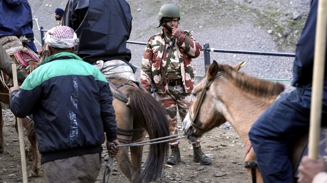 A security personnel stands guard as pilgrims proceeding to the holy cave shrine of Amarnath from Baltal. Credit: PTI Photo