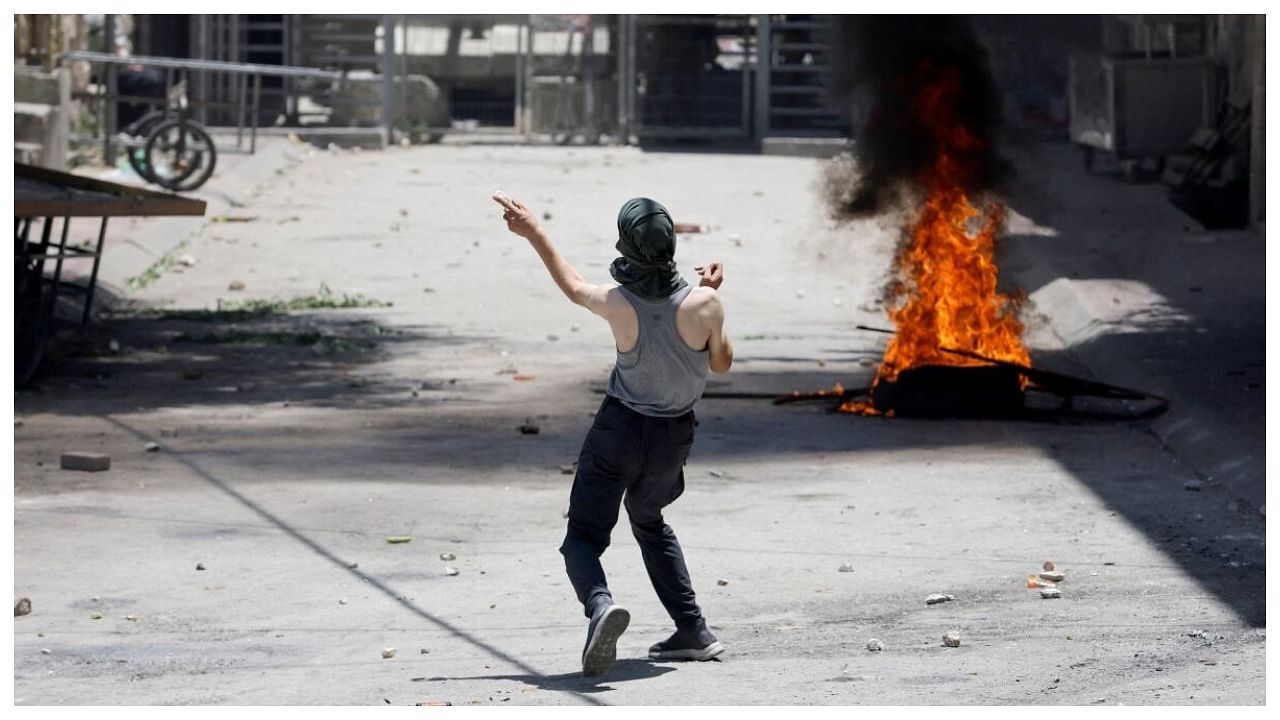 A Palestinian man throws stones during clashes over an Israeli military operation in Jenin, in Hebron, in the Israeli-occupied West Bank July 4, 2023. Credit: Reuters Photo