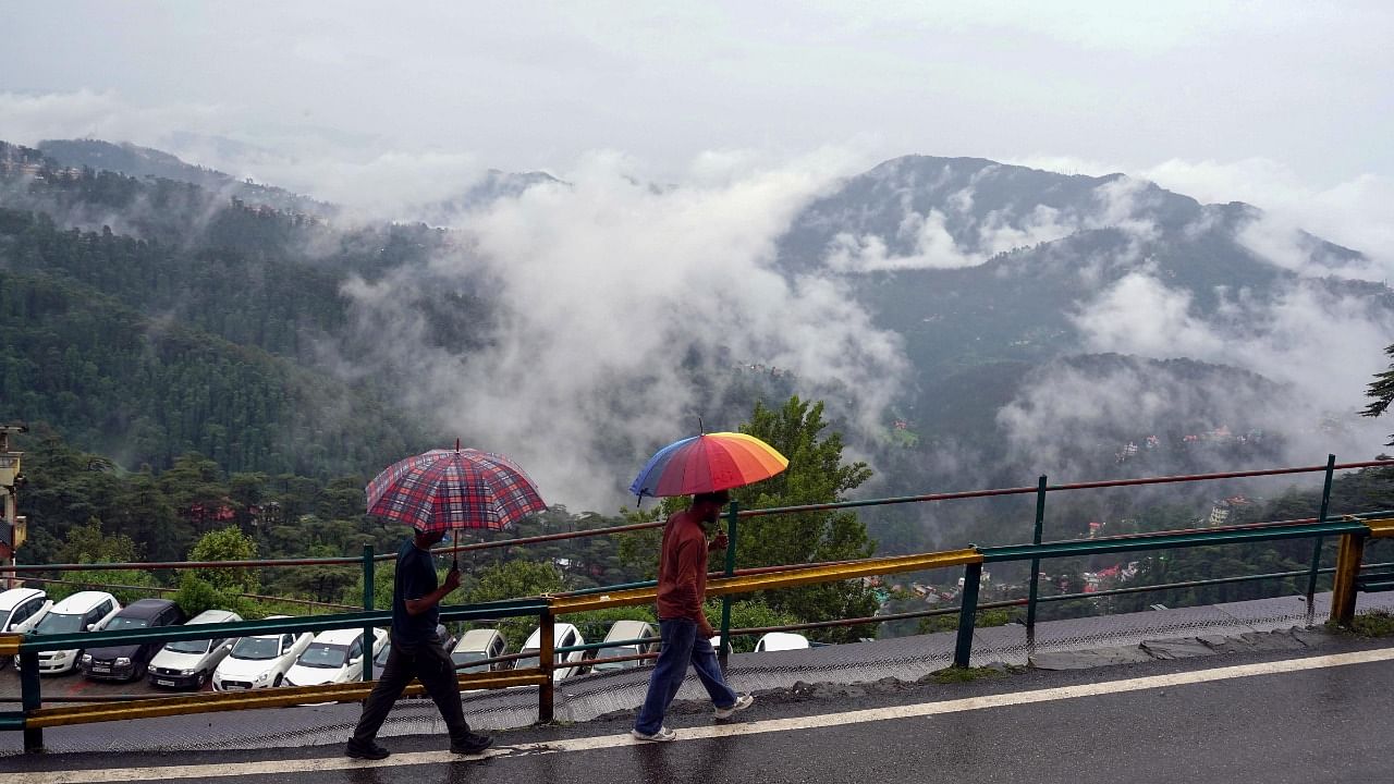 Pedestrians on a road during rain in Shimla. Credit: PTI Photo