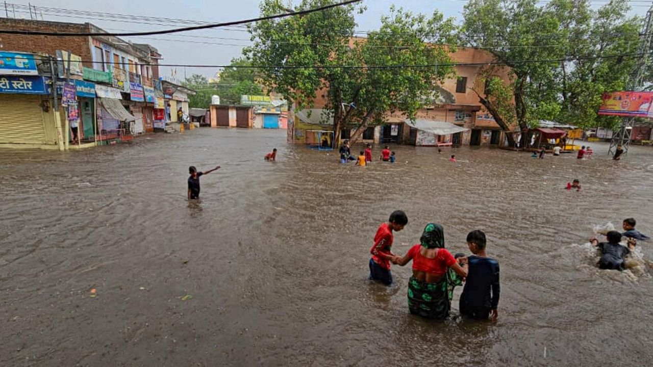 Locals wade through a flooded area after heavy monsoon rains, in Fatehpur, Wednesday, July 5, 2023.  Credit: PTI Photo